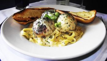 Jake and Telly's Specials - Chicken Meatball Pasta. A close up image of Chicken meatballs on a bed of pasta and smothered in a white parmesan black pepper cream sauce