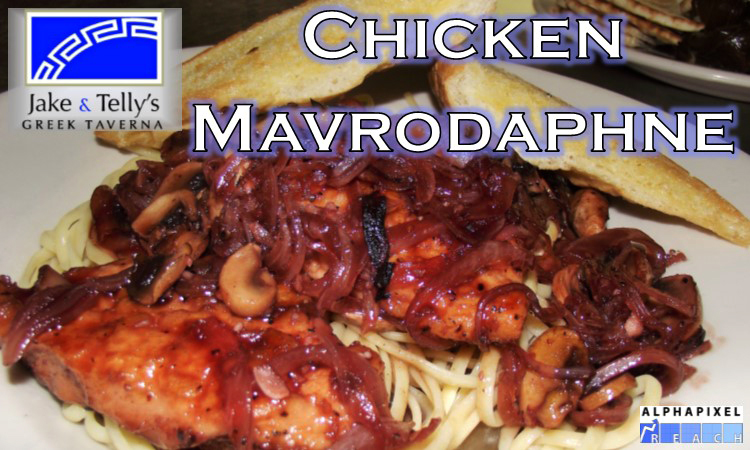 Entrees at Jake and Telly's: Chicken Mavrodaphne. A close up photo of our Chicken Mavrodaphne (Kóta Mavrodáphne). Chicken breast, with mushroom and onion, drenched in a Mavrodaphne-Port wine sauce and nestled on a bed of Fettuccine. Served with garlic bread. Jake and Telly’s Logo and the AlphaPixel Reach Logo are present.