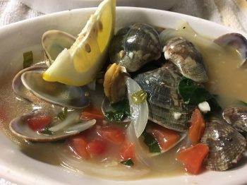 Appetizer: photo of Little Neck Clams in a white bowl. Little neck clams sautéed in garlic butter, white wine and fish fumé. Served with grilled bread.